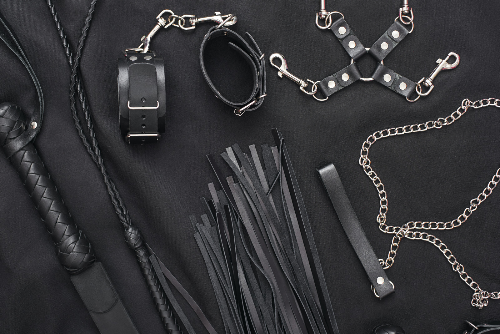 50 Shades of Grey. Top view of bdsm leather kit (whips, handcuffs, mask and chain) against of a 50 Shades of Grey. Top view of bdsm leather kit (whips, handcuffs, mask and chain) against of a
